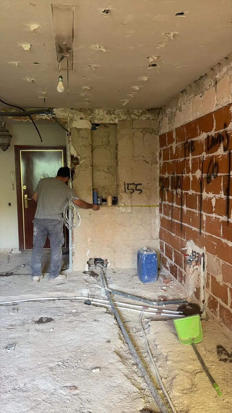 Operario tomando medidas sobre el muro de ladrillo tras la demolición