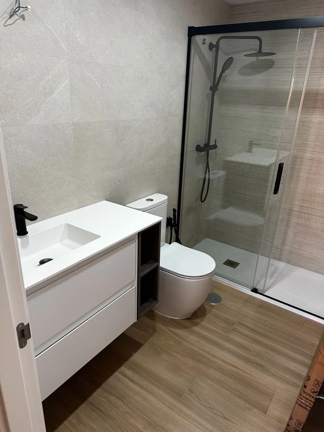 Baño terminado con mampara negra y mueble blanco a medida